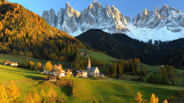 Scenic Switzerland village with autumn trees and snow covered mountains in the background