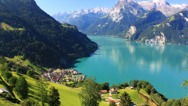Stunning Switzerland landscape with green hills and clear blue lake surrounded by mountains