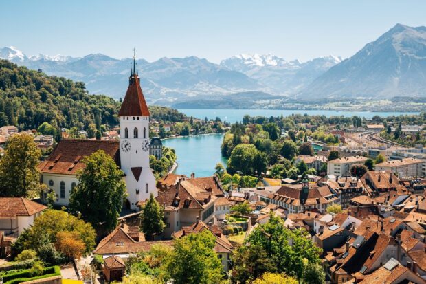 A charming town in Switzerland with a historic clock tower and lake surrounded by mountains