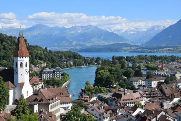 A scenic view of Switzerland with mountains and a river surrounded by town buildings