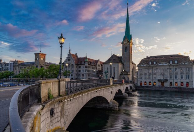 Historic buildings and a stone bridge over a river in Switzerland at sunset