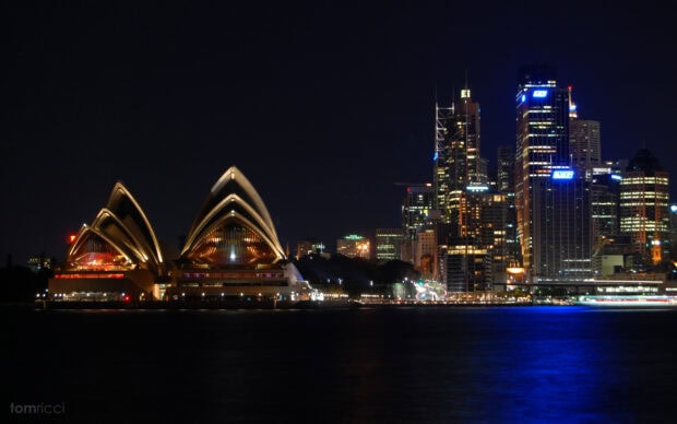 Sydney city skyline with illuminated landmarks at night including iconic architecture and high rise buildings