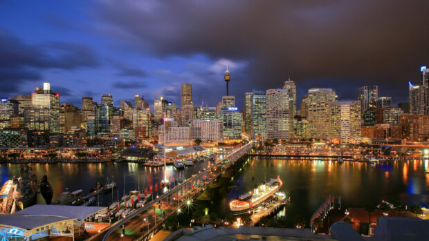 Sydney city skyline at night with lights reflecting on the harbor water