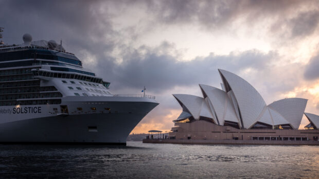 Cruise ship near Sydney Opera House with cloudy sky at sunset
