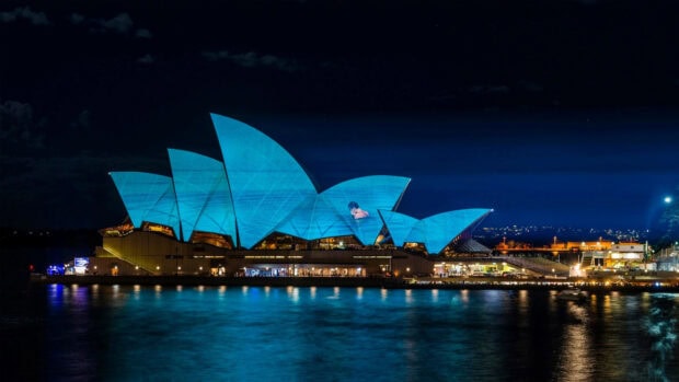 Sydney Wallpaper 4K Desktop Night view of iconic Sydney sails illuminated in blue color on water reflection
