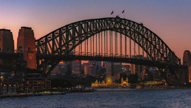 Sydney steel arch bridge with city skyline during sunset light