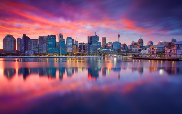 Sydney city skyline with colorful sunset reflecting on calm water
