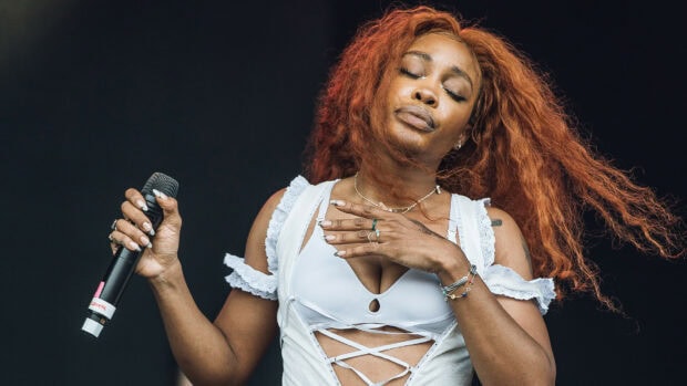 Sza performing on stage with closed eyes and vibrant red hair