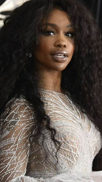 Close up of Sza wearing a white beaded dress with long curly hair
