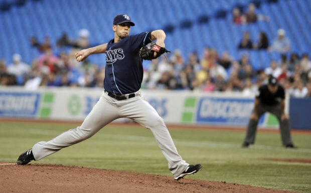 A Tampa Bay Rays baseball player pitching on the mound during a game with fans in the background