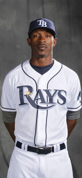 A Tampa Bay Rays player wearing a white uniform and cap standing against a gray background