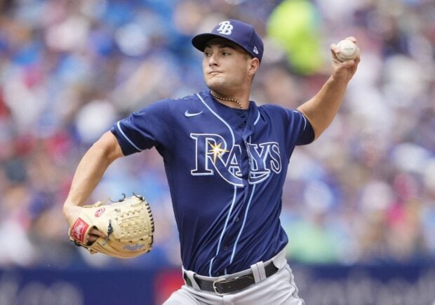 A Tampa Bay Rays player pitching during a professional baseball game on a sunny day