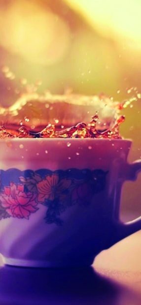 A floral cup with tea splashing out in vibrant colors