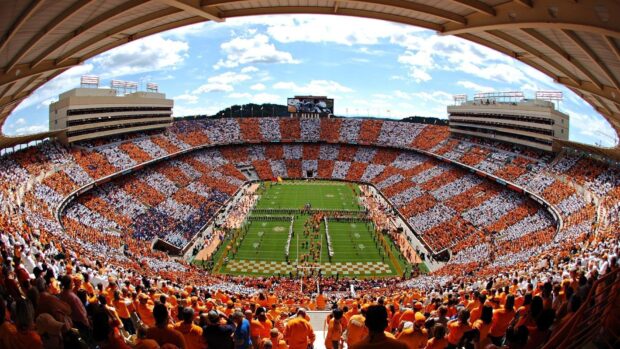 A large crowd fills the Tennessee stadium with fans wearing orange and white creating a checkerboard pattern