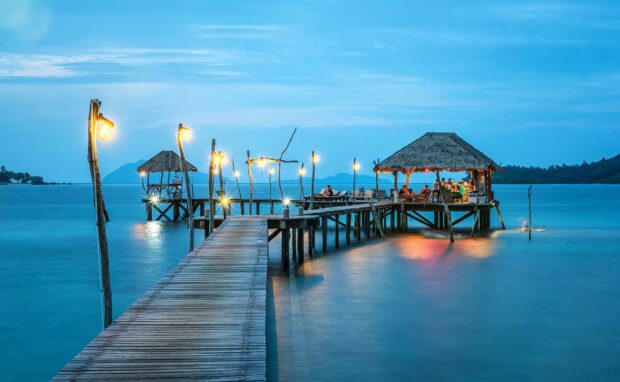 A peaceful Thailand pier with lamps and a traditional pavilion over calm blue sea at dusk