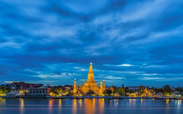 Wat Arun temple illuminated at dusk in Thailand cityscape