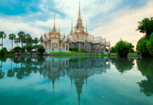 A beautiful Thailand temple reflected in serene water with lush greenery around