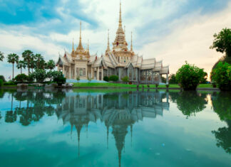 A beautiful Thailand temple reflected in serene water with lush greenery around