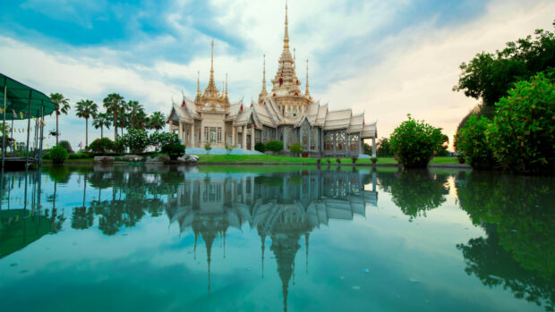 A beautiful Thailand temple reflected in serene water with lush greenery around