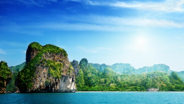 Limestone cliffs covered in lush greenery along the coastline of Thailand