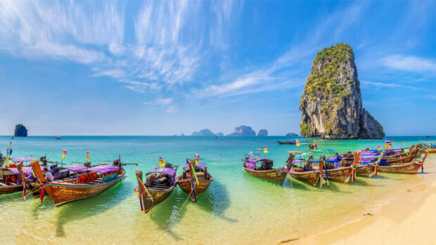Traditional longtail boats anchored on clear turquoise waters in Thailand bay