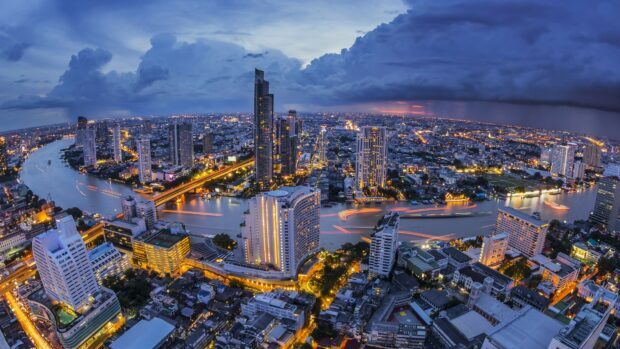 A vibrant Thailand cityscape with rivers and illuminated skyscrapers at twilight showcasing urban life