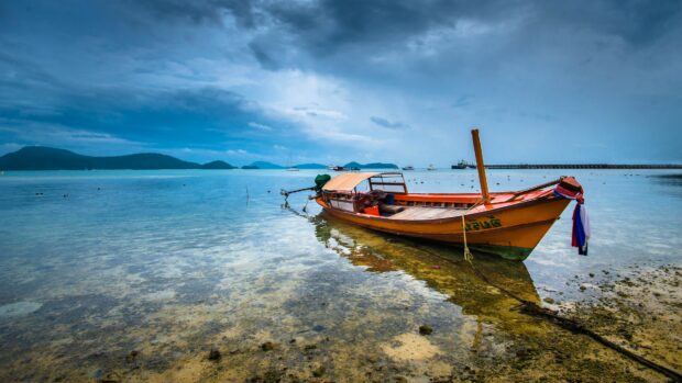 Traditional Thai boat resting on calm clear water near the shore in Thailand