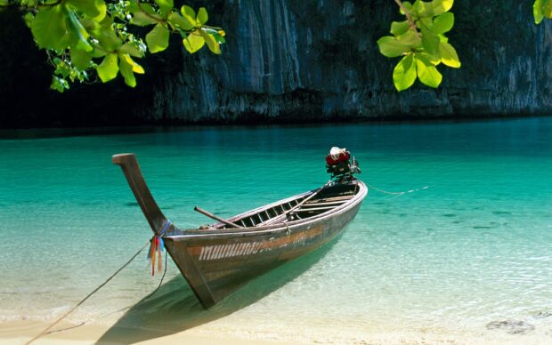 Traditional longtail boat on clear turquoise water in Thailand bay
