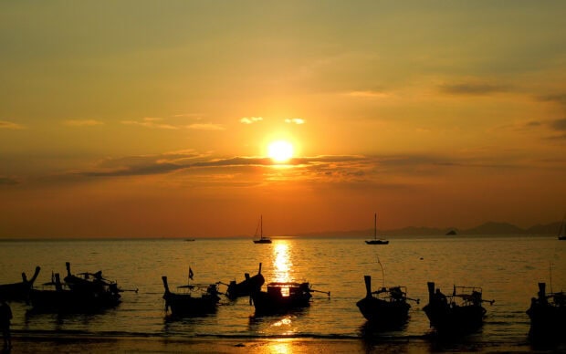 Traditional Thai boats floating on the sea during a beautiful sunset in Thailand