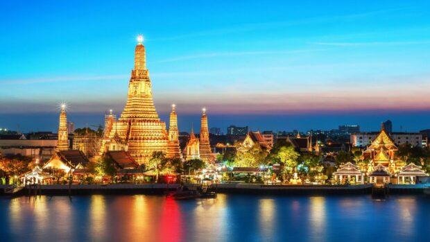 Iconic Thailand temple at sunset with clear sky and river reflections