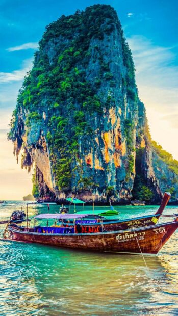 Traditional Thai longtail boat near limestone cliff in Thailand sea
