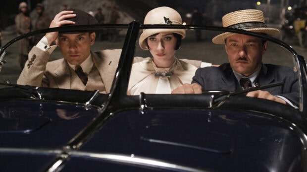 The Great Gatsby characters dressed in vintage attire sitting in a classic car