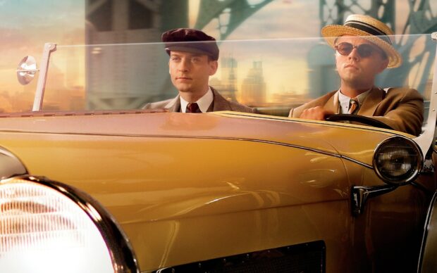 Two men sitting in a vintage car wearing classic 1920s attire from The Great Gatsby