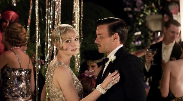 A scene from The Great Gatsby featuring a woman in a flapper dress dancing with a man in a tuxedo at a party