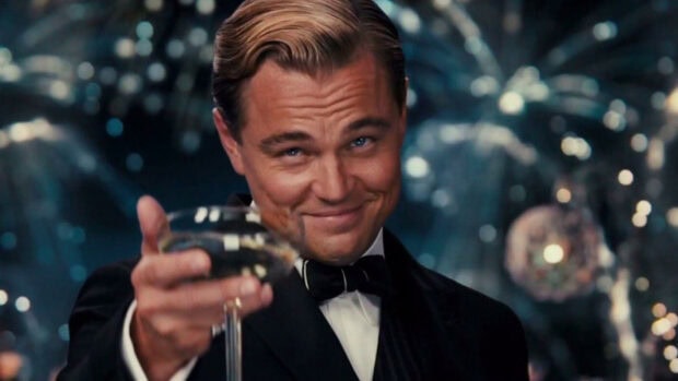 The Great Gatsby character wearing a tuxedo raising a glass for a toast