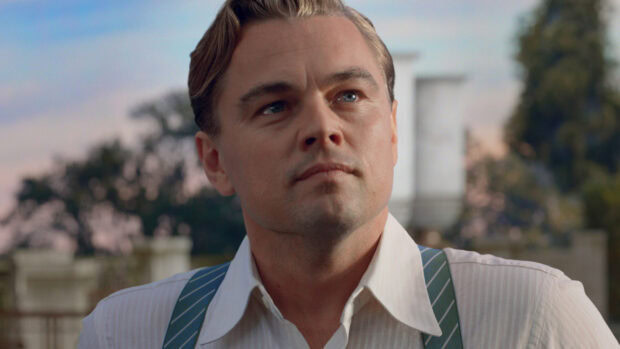 The Great Gatsby character in a white shirt looking thoughtfully outdoors