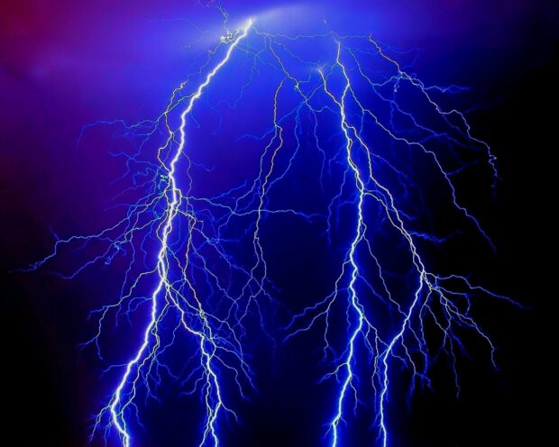Bright electric thunder bolts illuminating the dark blue sky with vivid energy