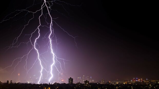 Bright lightning strikes over city skyline at night thunder