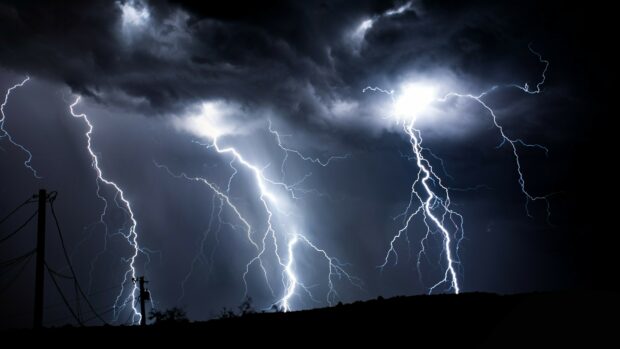 Multiple bright thunder strikes lighting up the dark sky during a storm
