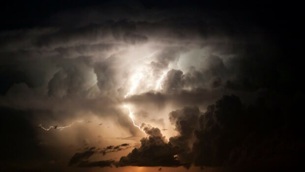 A powerful thunderstorm with bright lightning striking through dense dark clouds at night