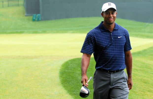 Tiger Woods walking on the golf course holding a golf club in his hand