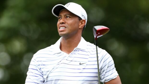 Tiger Woods wearing a white striped shirt and cap holding a golf club during a tournament