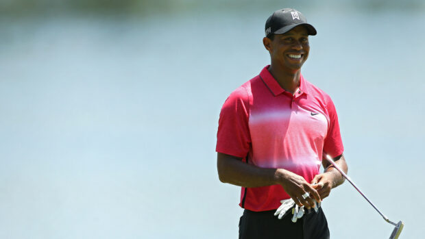 Tiger Woods smiling and holding golf club on golf course during a game