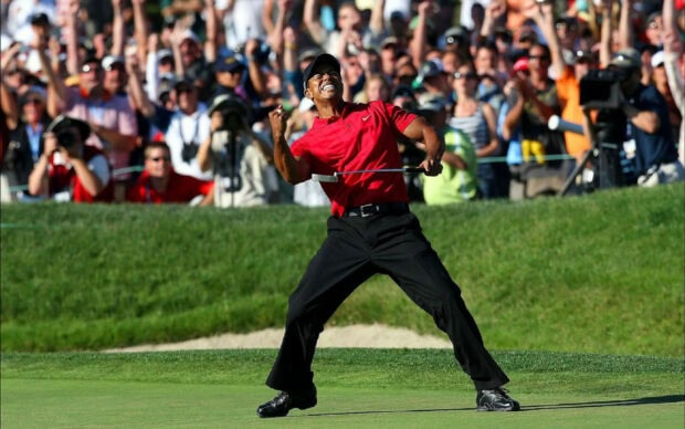 Tiger Woods celebrating a golf win in front of a cheering crowd on the green