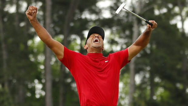 Tiger Woods celebrating a victorious moment on the golf course in a red shirt