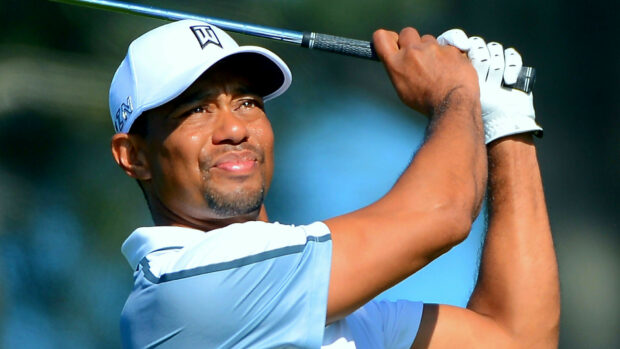 Tiger Woods focusing on his golf swing during a tournament in bright sunlight