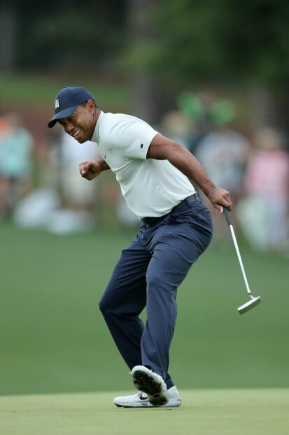 Tiger Woods celebrating a golf win with a putter on the green in a golf tournament