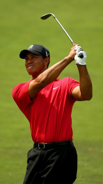 Tiger Woods swinging a golf club on a green field during a game