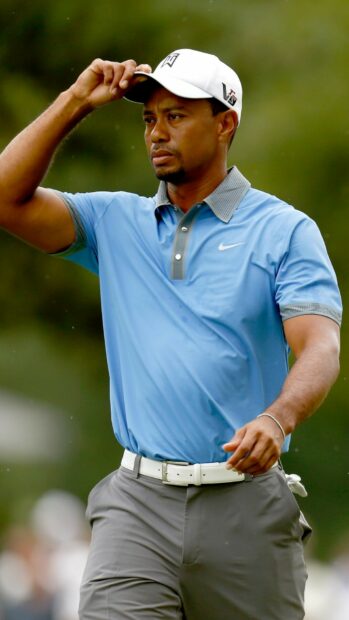 Tiger Woods wearing a blue shirt and white cap on the golf course