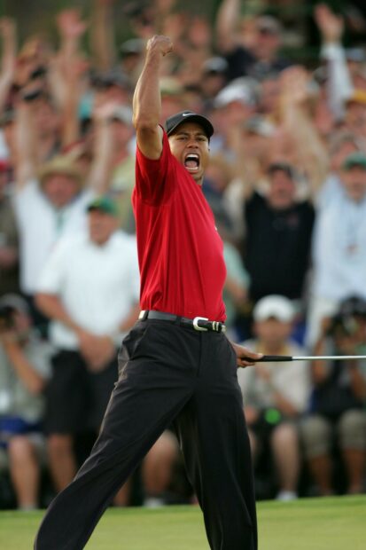 Tiger Woods celebrating a golf victory wearing a red shirt and black pants on the course